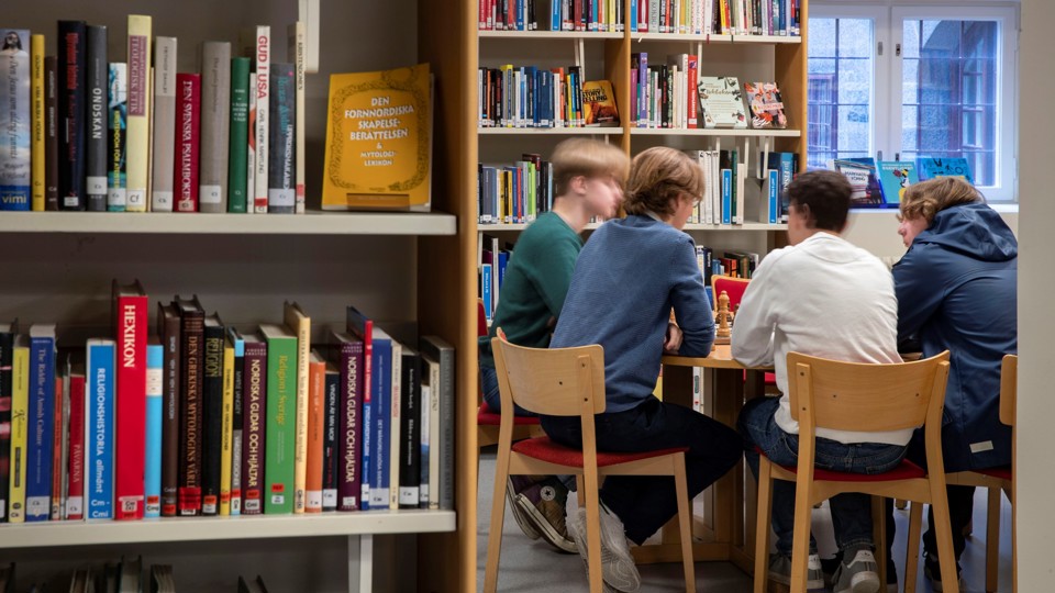 Elever sitter vid ett bord i biblioteket på Östra Reals gymnasium