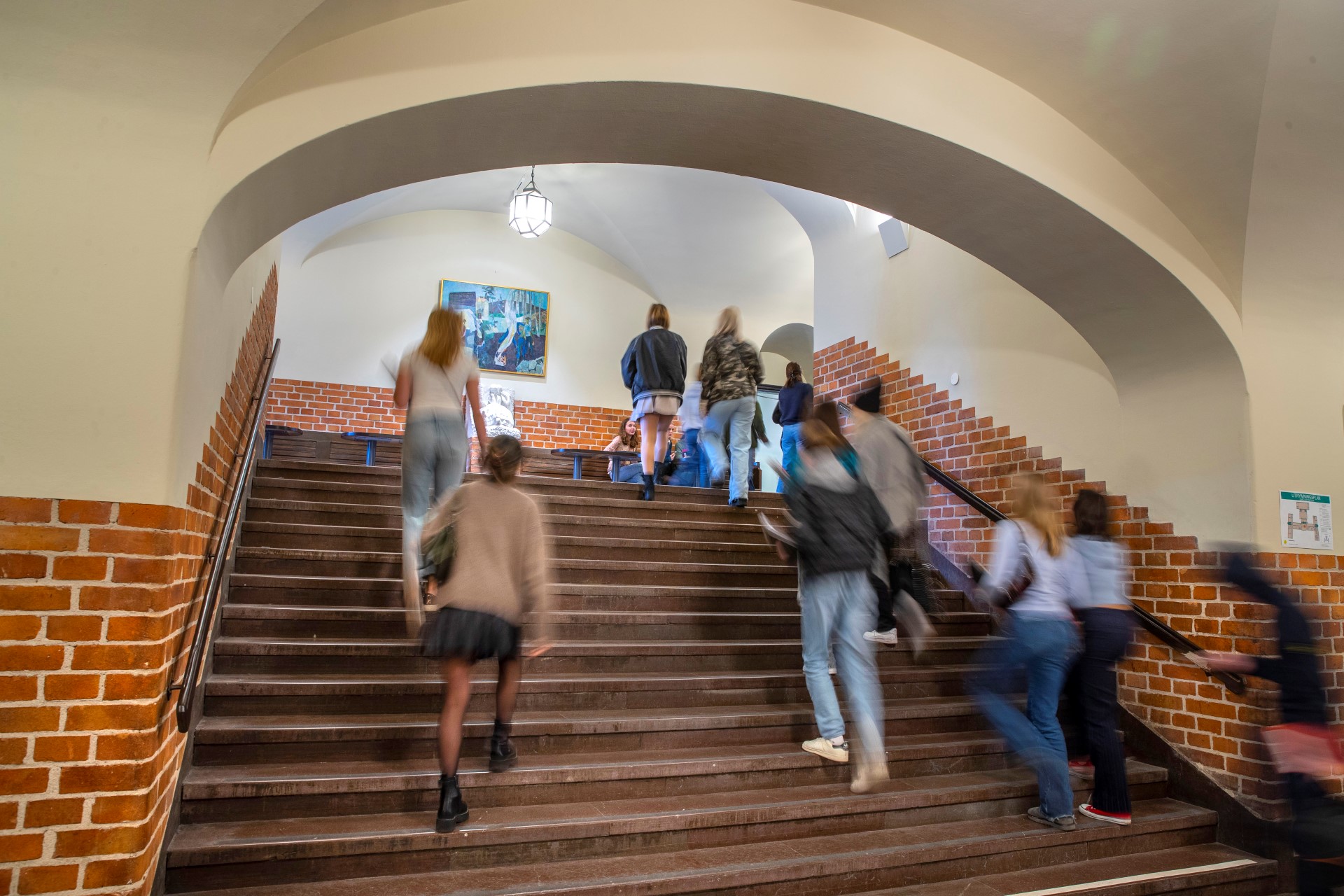 Elever går i en stentrappa inomhus på Östra Reals gymnasium